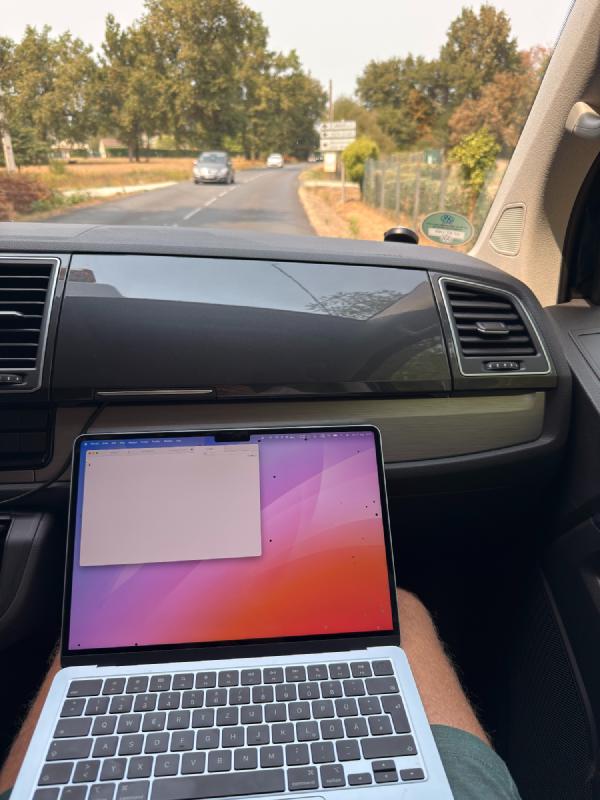 Photo of MacBook on lap while seated in the passenger seat on a car